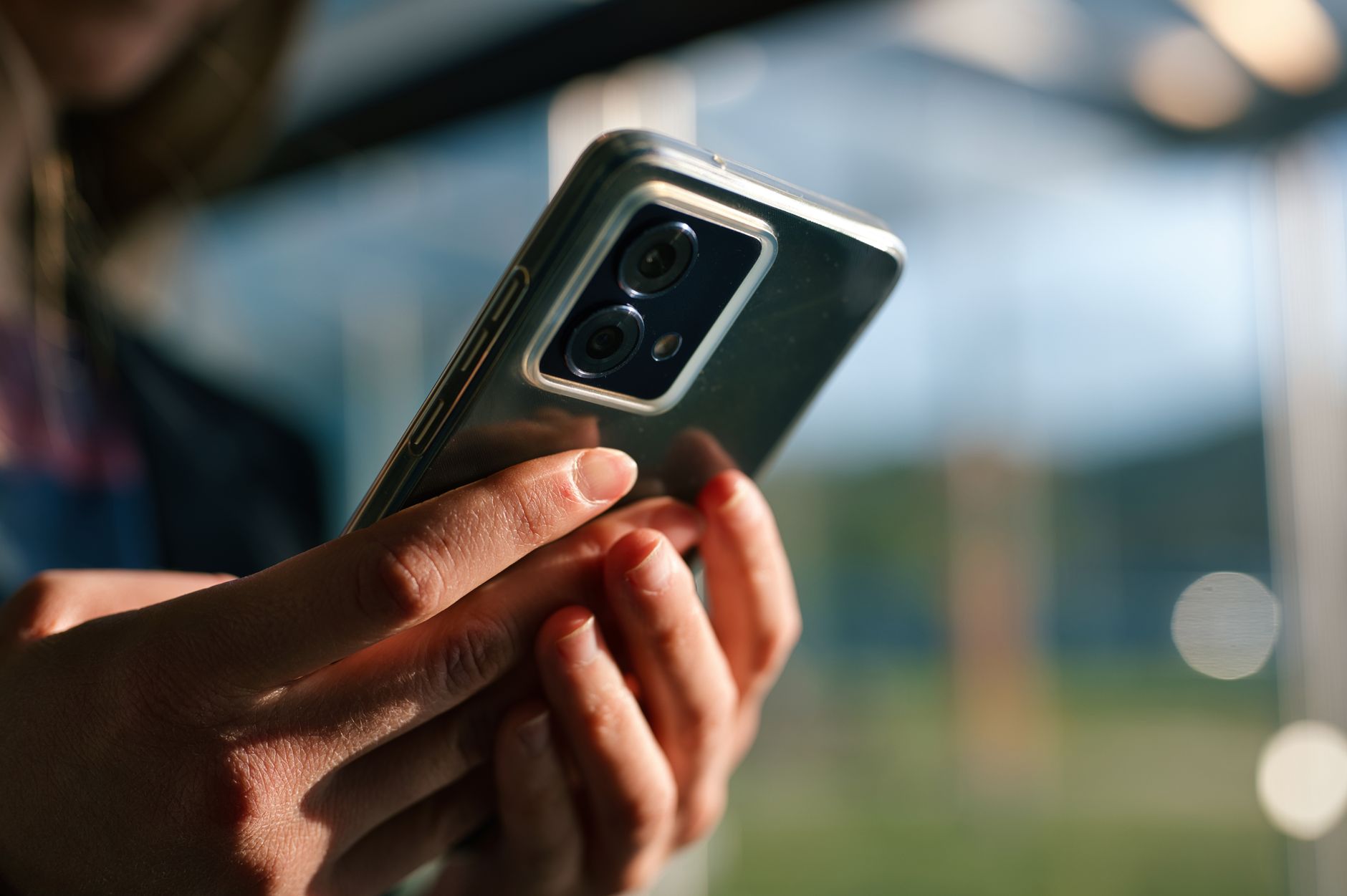 close up of hands holding a smartphone outdoors